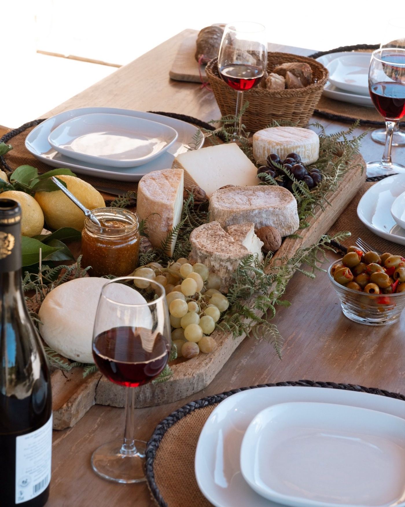 Planche de fromages corses, pain et deux verres de vin rouge sur une table en bois