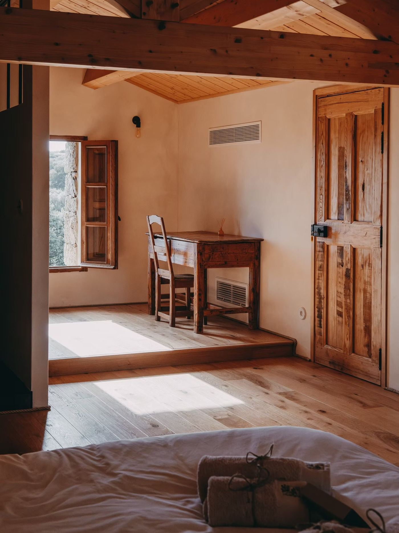 Un bureau en bois sous la fenêtre de la chambre
