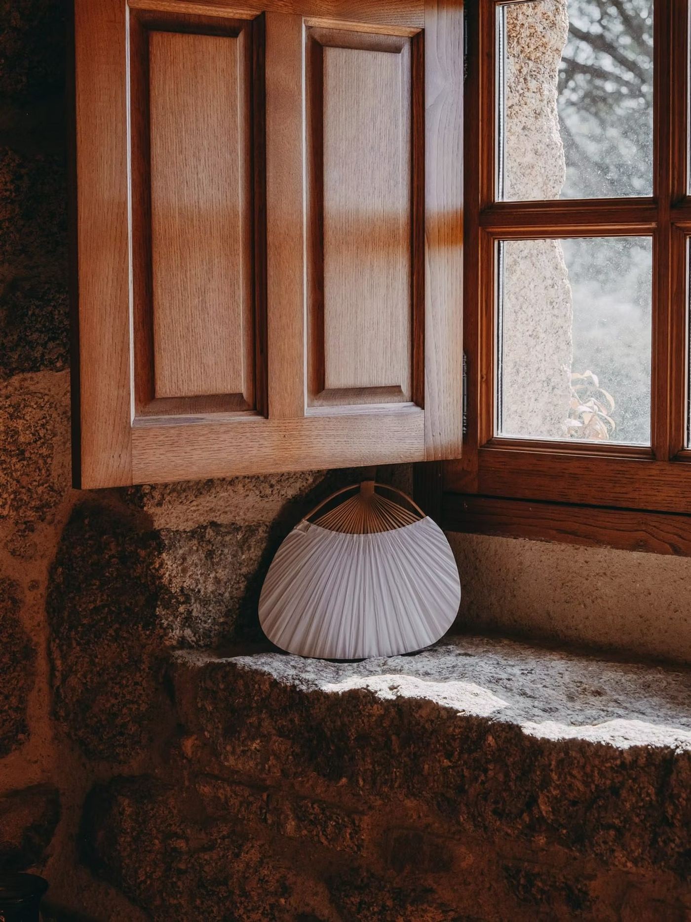 Une banquette de granit sous une fenêtre aux volets de bois