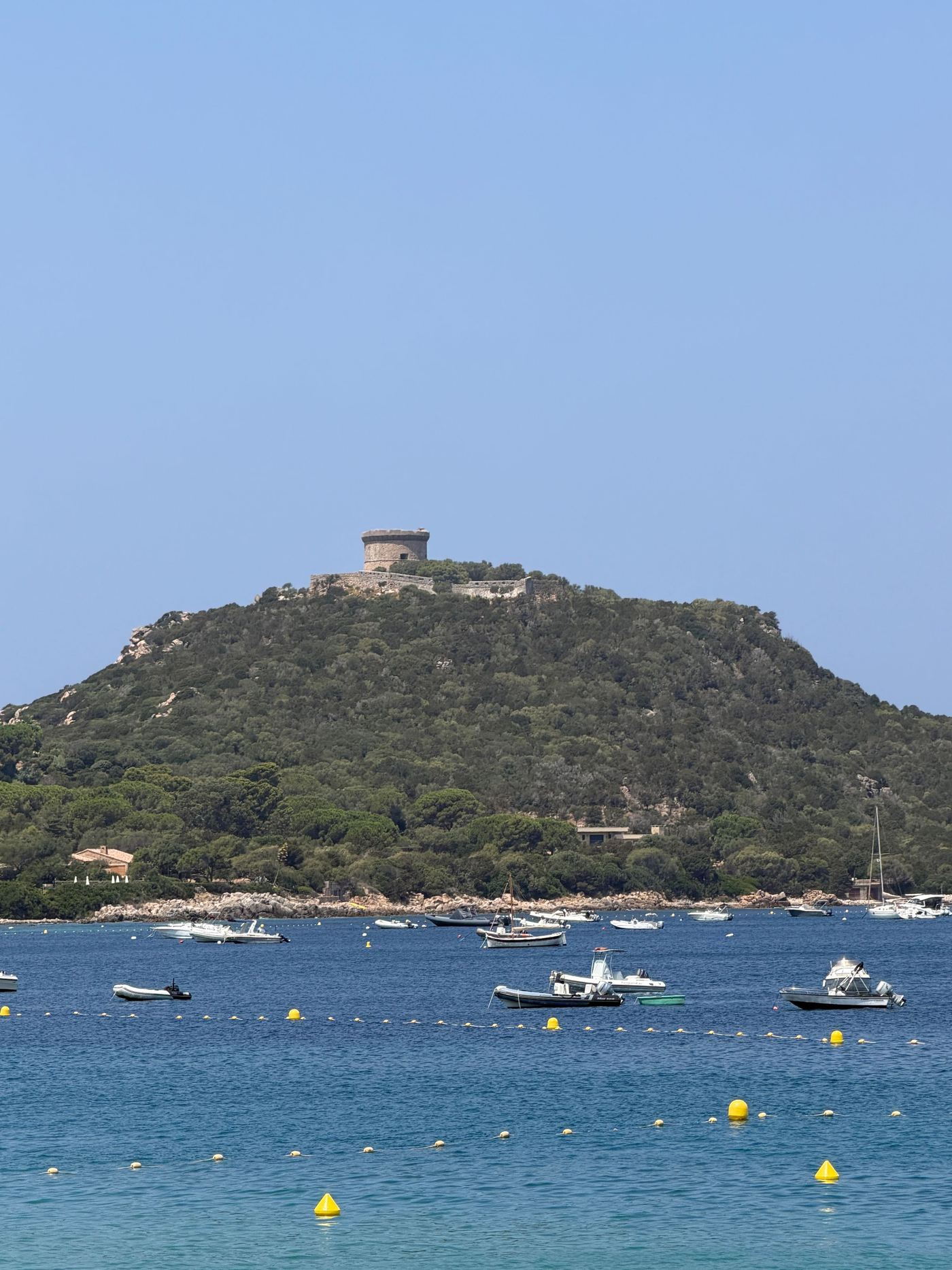 La tour génoise de Campomoro sur son promontoire, bateaux dans la baie