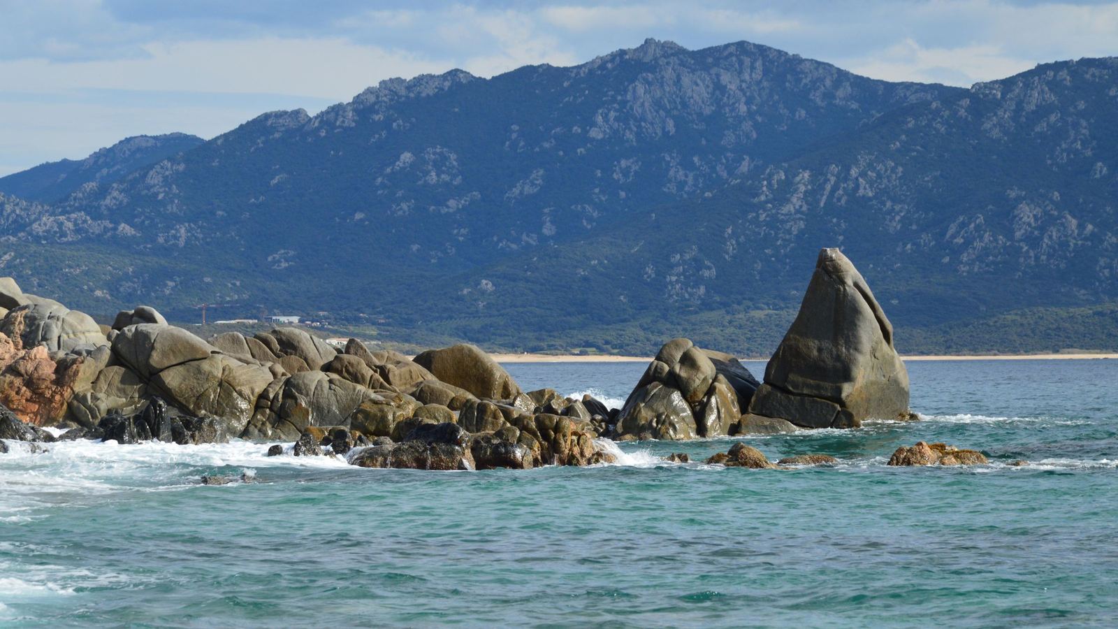 Rochers de granit et eau turquoise sur la côte du golfe du Valinco, montagnes au fond